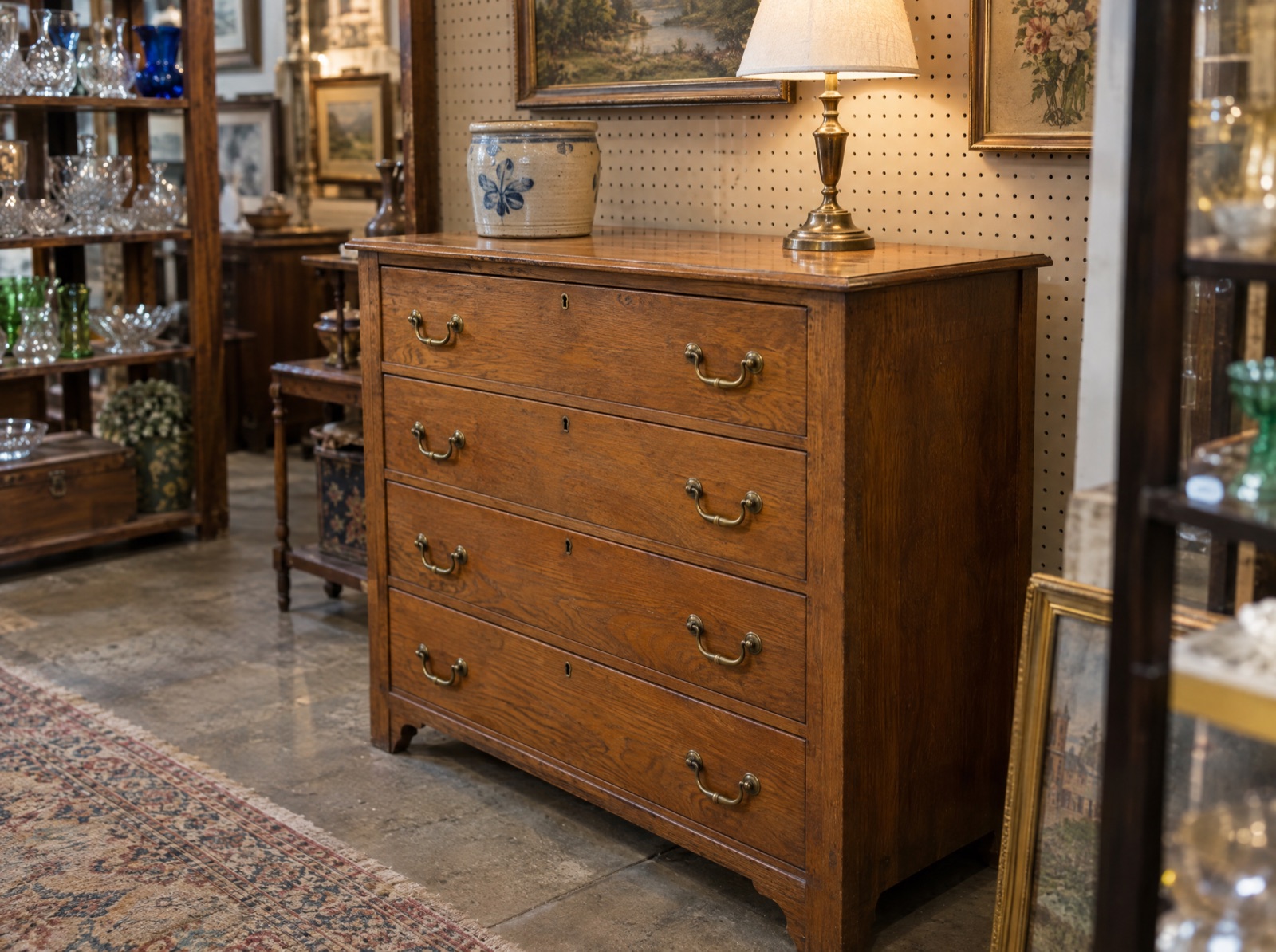 An oak dresser with brass pulls standing in an antique mall booth